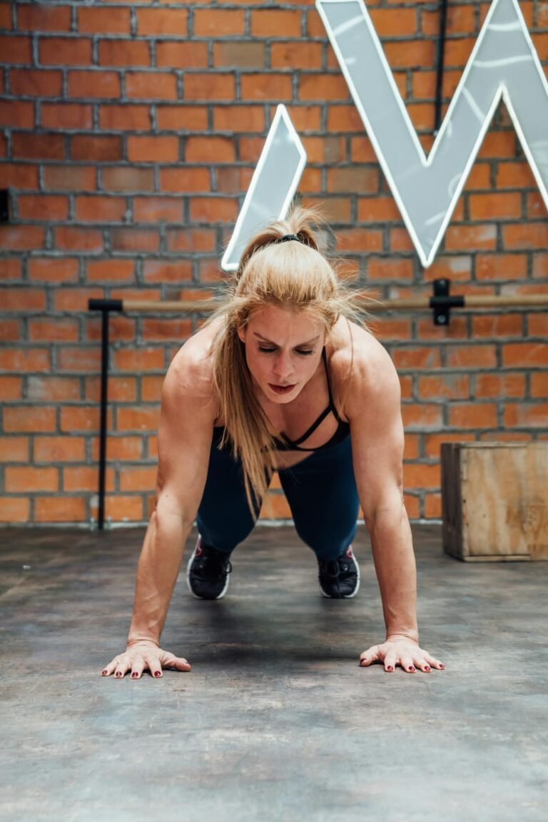 Fit woman doing push-ups in a gym with exposed brick walls, showcasing strength and focus.